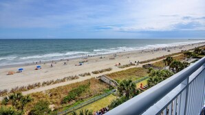 A beach with a view of the ocean, a pier in the distance, and a grassy area with a fence. - GRAND ATLANTIC RESORT 601 - 3 Bedroom Condo by RedAwning (Myrtle Beach)