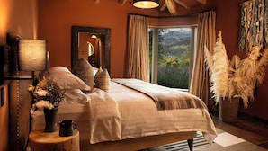 Een slaapkamer met een groot bed, een nachtkastje met een lamp, een spiegel en uitzicht op de omgeving.