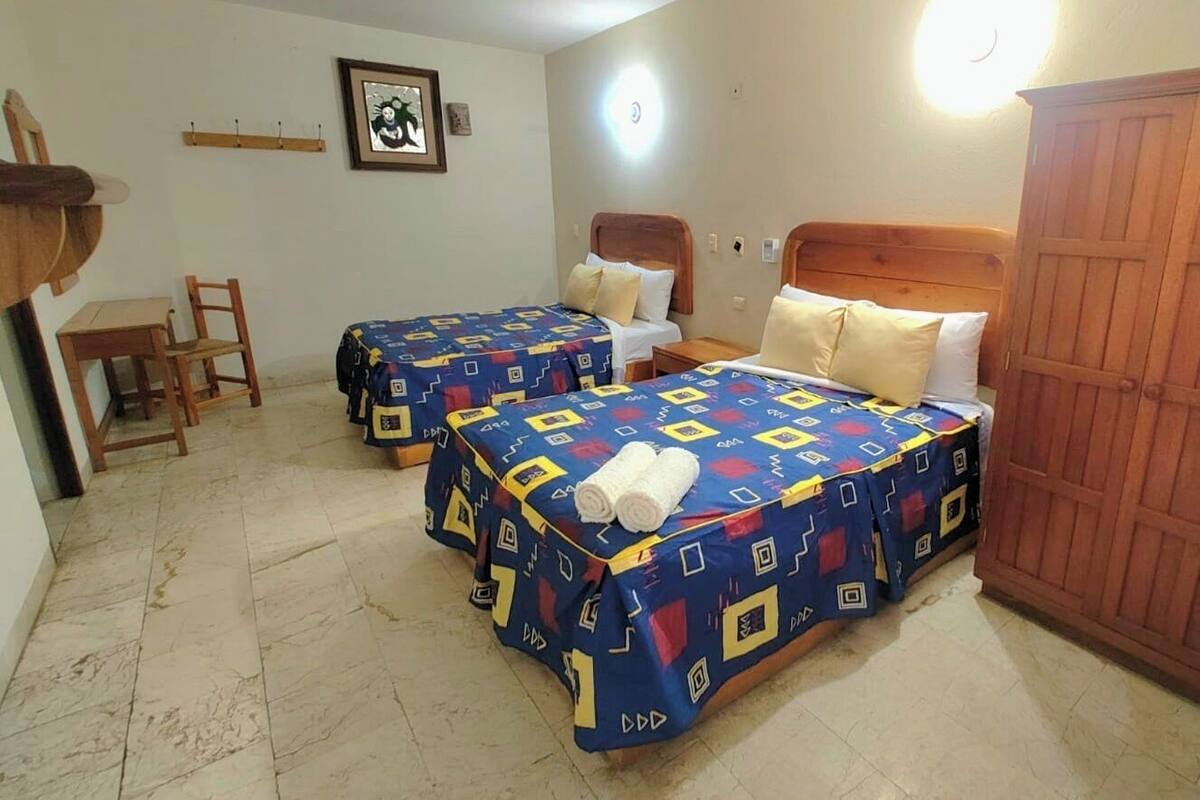 A room with two beds, a wooden wardrobe, a small table, and a chair.