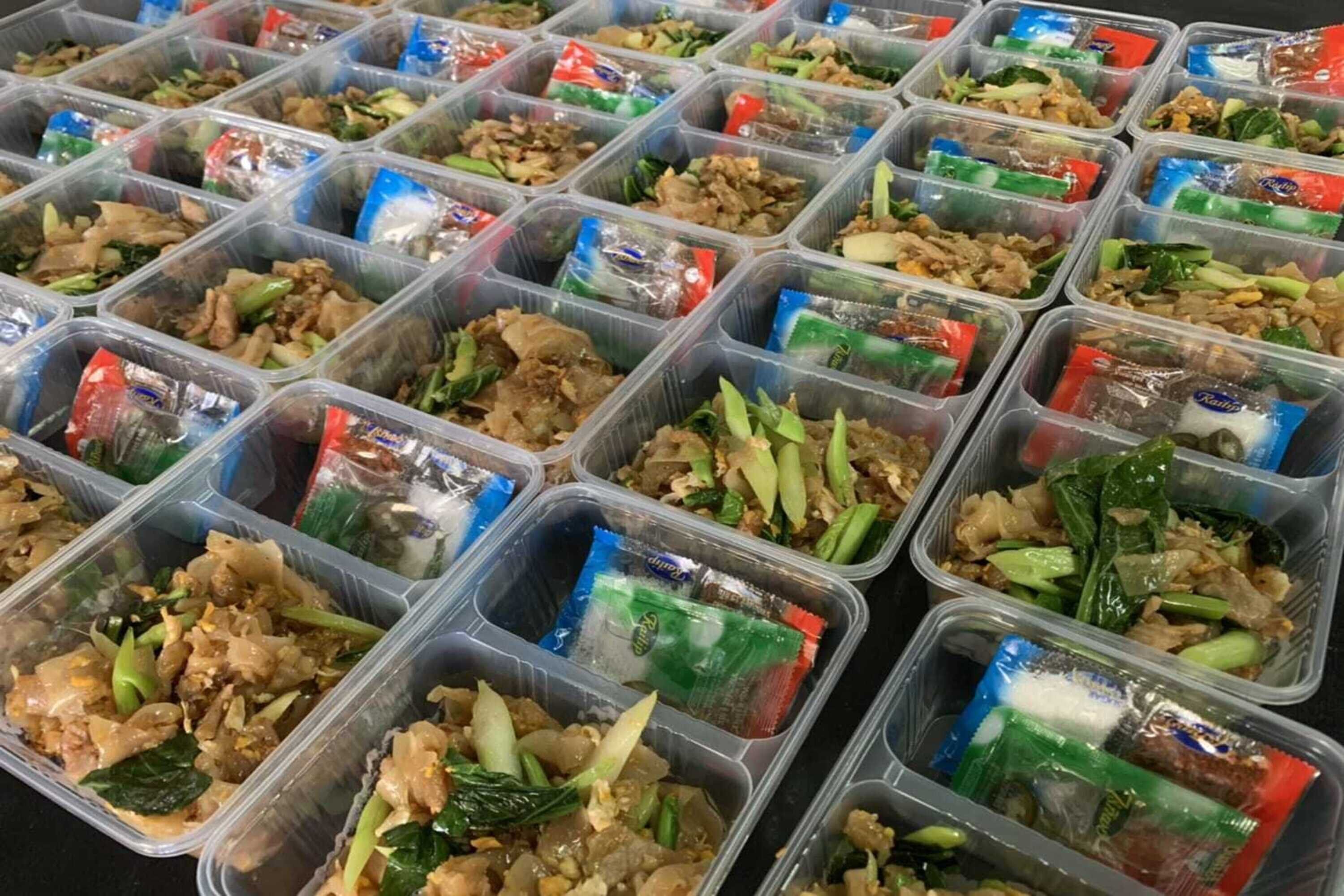 Multiple plastic containers filled with various food items, including vegetables and meat, arranged in rows.