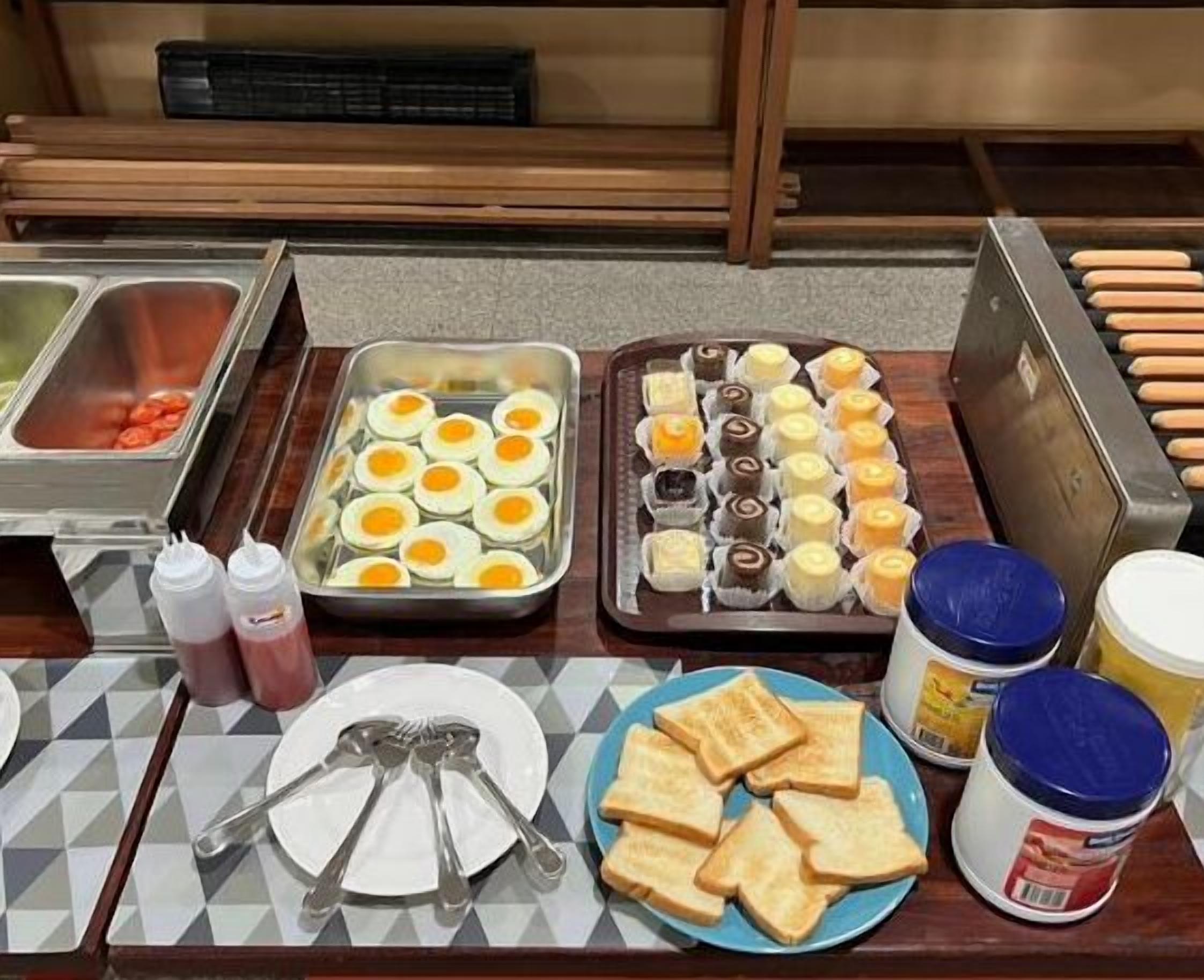 Un buffet proposant une variété de plats, notamment des œufs, des viennoiseries et du pain.