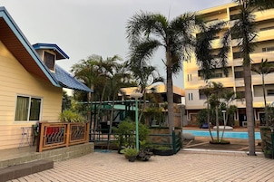 Un patio con piscina, palmeras y un edificio de techo azul.