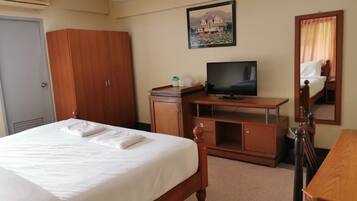Una habitación de hotel con cama, televisión, armario y escritorio.