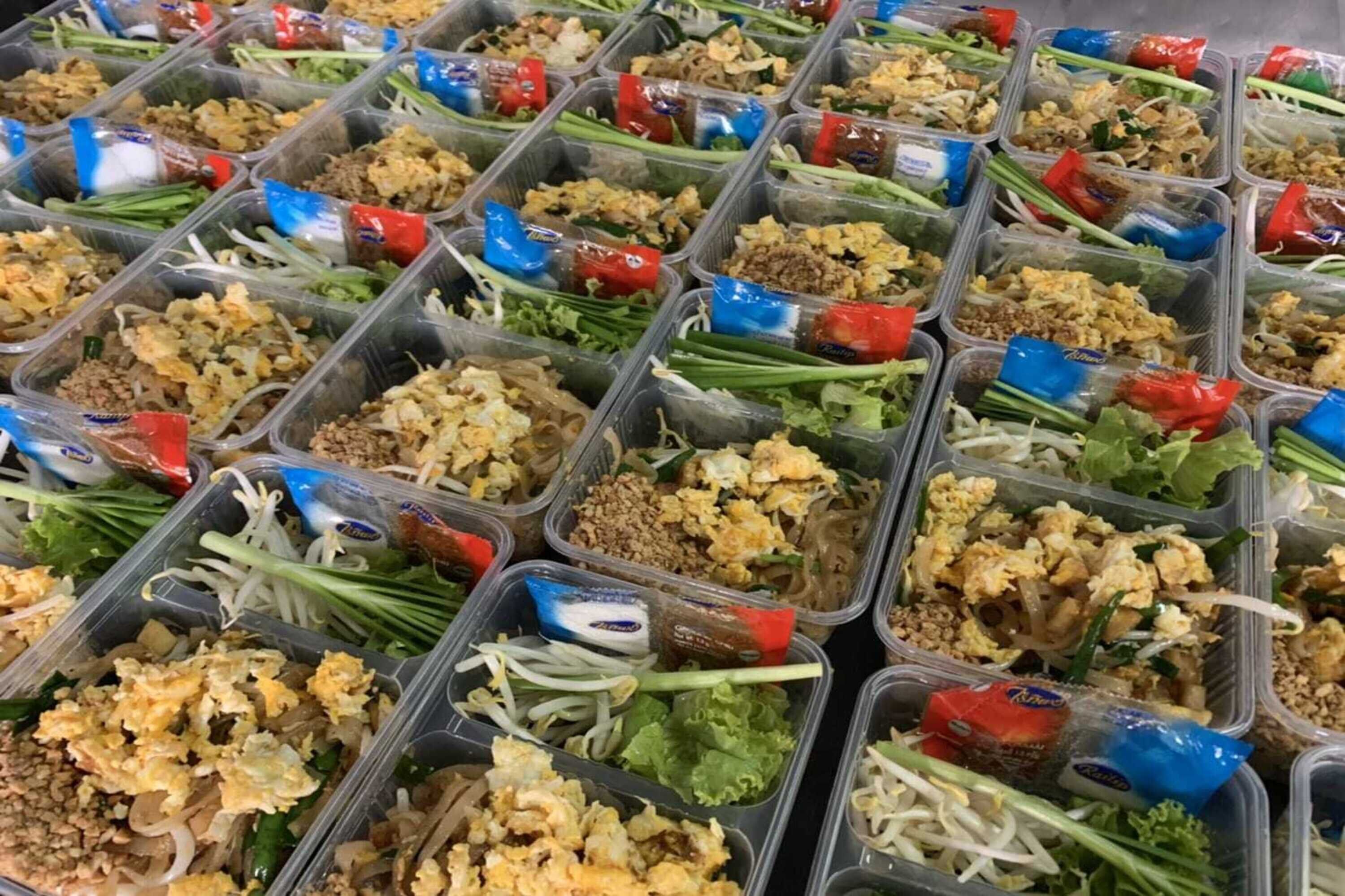 Multiple plastic containers filled with various food items, including noodles, vegetables, and sauces.