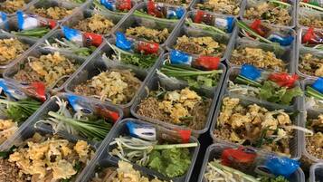 Multiple plastic containers filled with various food items, including noodles, vegetables, and sauces.