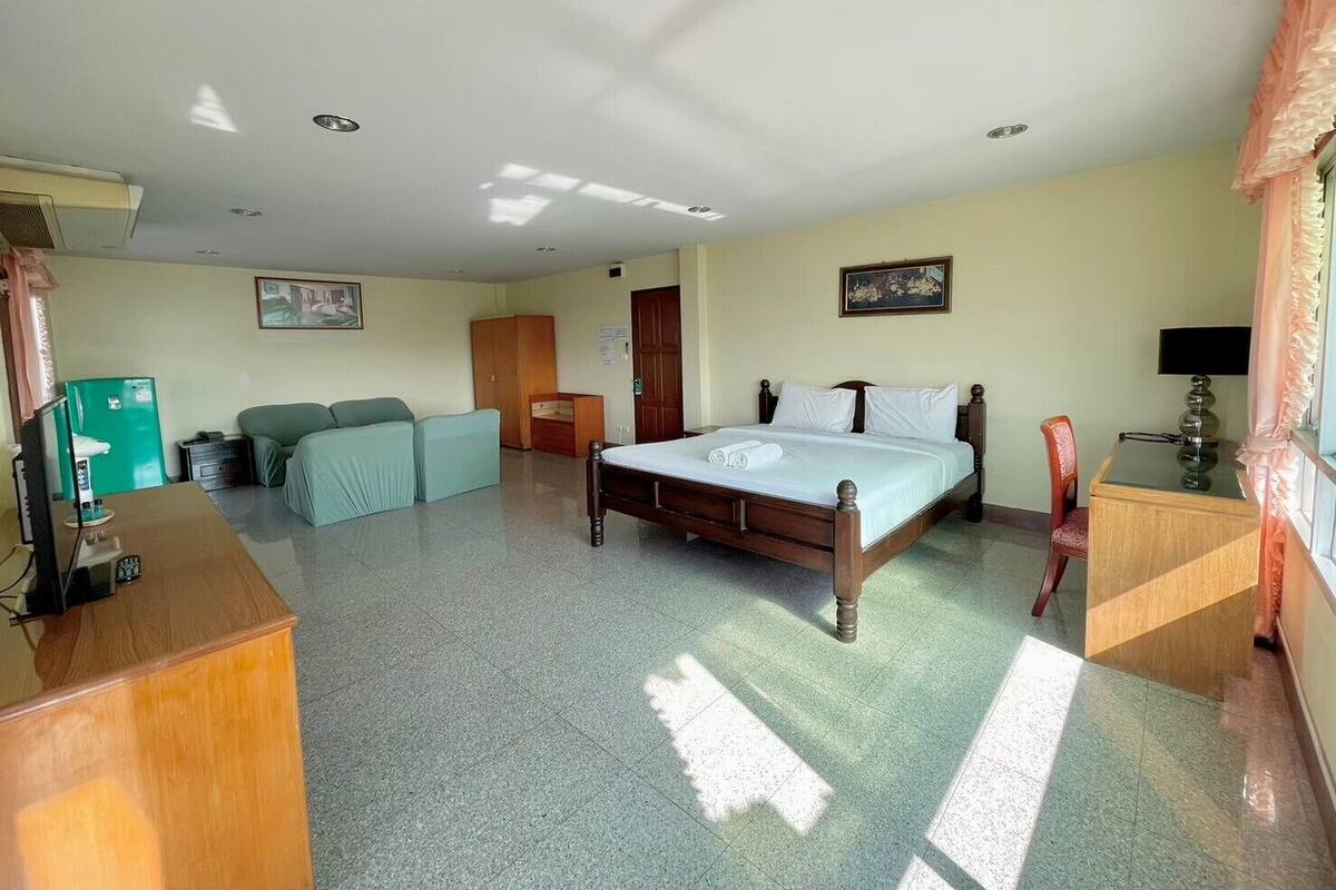 A hotel room with a bed, a desk, a chair, a wardrobe, and a television.