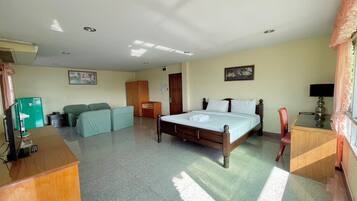 A hotel room with a bed, a desk, a chair, a wardrobe, and a television.