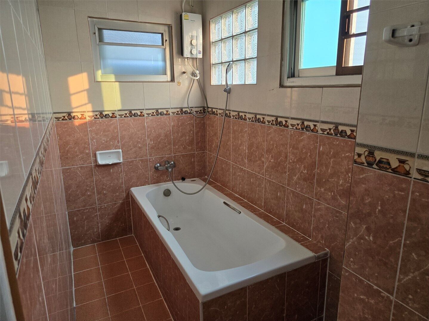 Un baño con bañera, ventana y ducha.