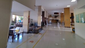 A spacious lobby with a seating area, a fire extinguisher, and a potted plant.