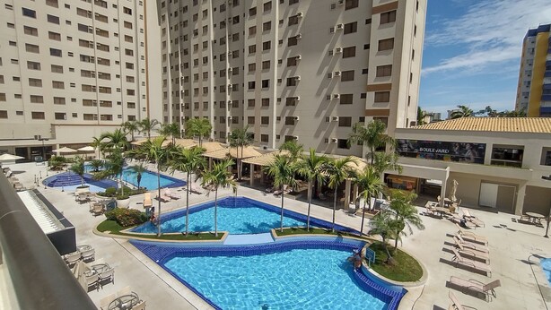 A hotel with multiple swimming pools, palm trees, and lounge chairs.