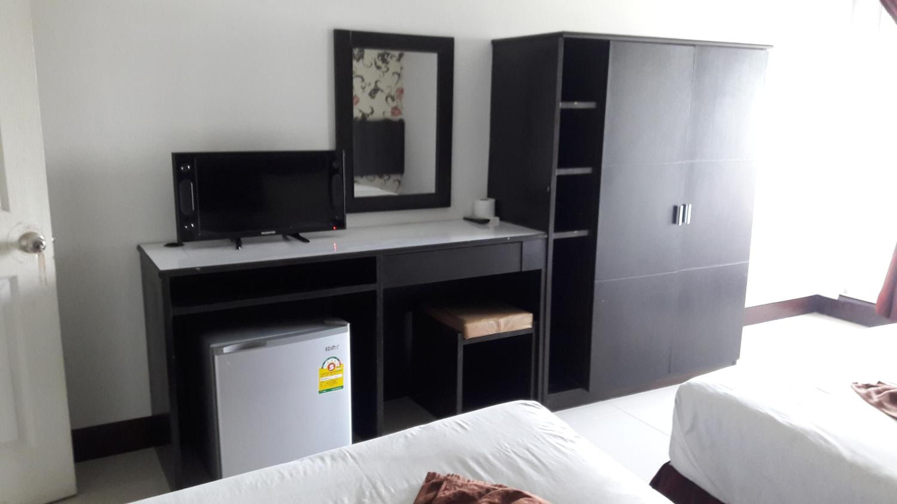 Une chambre d’hôtel comprenant un lit, un bureau avec un ordinateur, un petit réfrigérateur et une armoire.