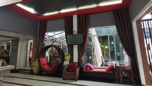 Un espace de détente moderne avec un fauteuil suspendu, des canapés et une grande fenêtre offrant une vue sur l’extérieur.