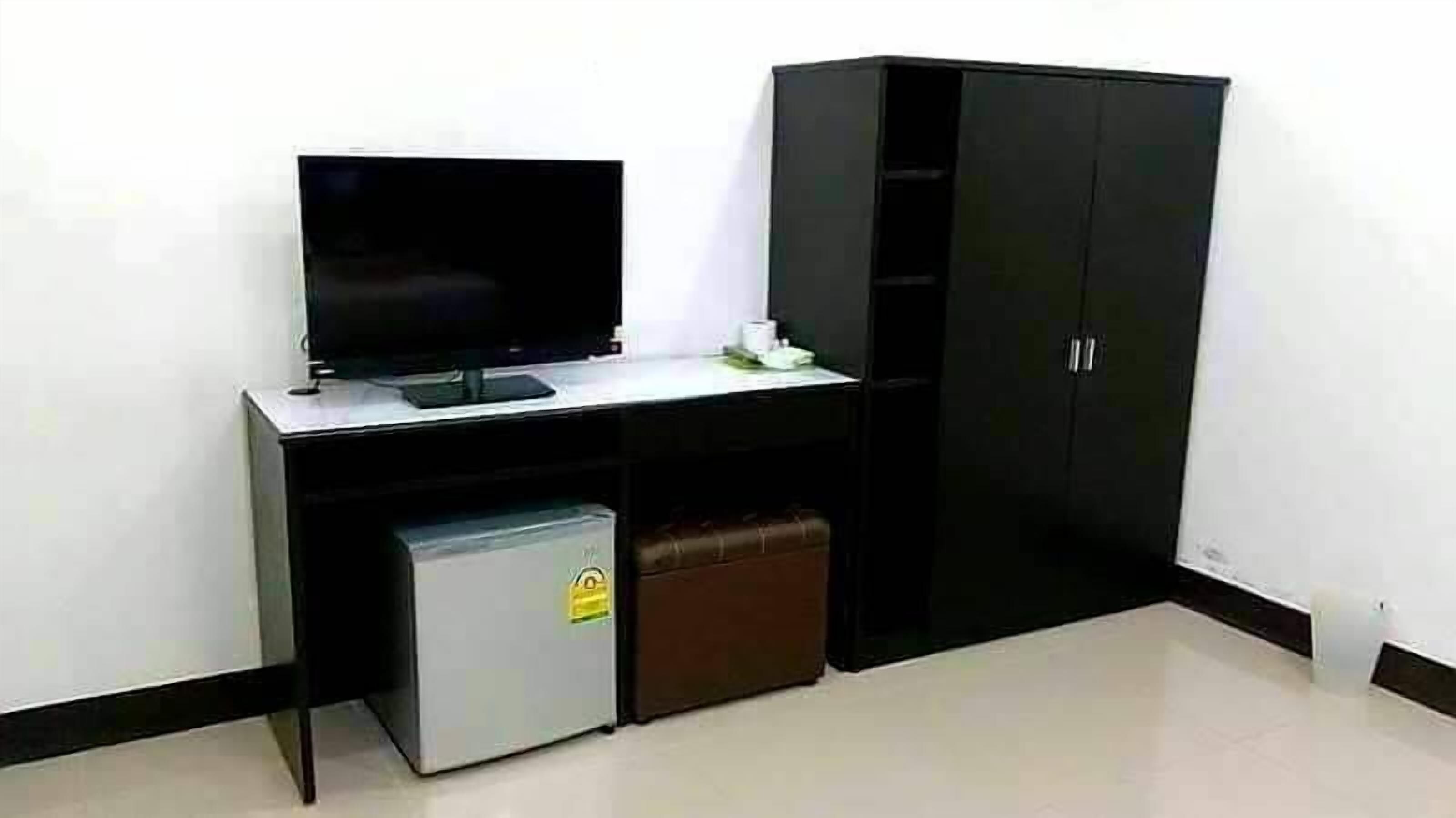 A room with a TV, a small refrigerator, and a black wardrobe.