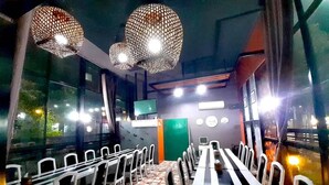 Un restaurant avec un long comptoir, des chaises blanches et des luminaires suspendus.