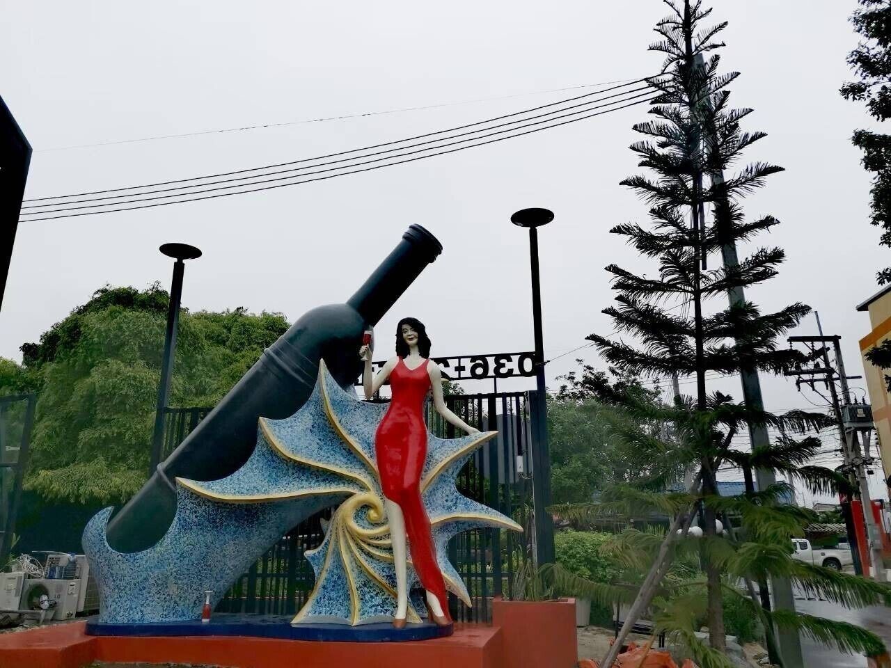 Una estatua de una mujer con vestido rojo, de pie junto a una gran estructura decorativa.