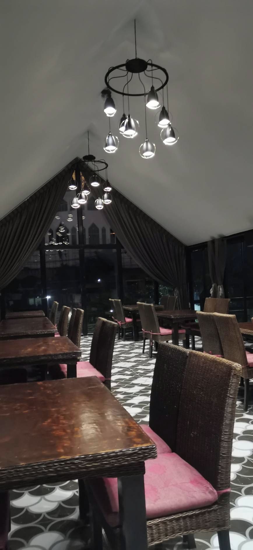Un ristorante con tavoli e sedie, un pavimento decorato e un soffitto con lampade a sospensione.
