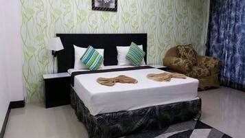 A neatly arranged bedroom with a bed, a nightstand, a chair, and a patterned wall.