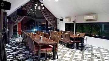 A dining area with a high ceiling, pendant lighting, and a patterned floor.