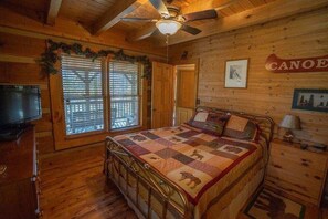 A cabin-style bedroom with a wooden ceiling, a bed with a quilt, a ceiling fan, and a television on a wooden cabinet. - Secluded yet close to everything! (Vilas)