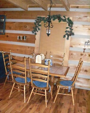 A wooden dining table with four chairs, a chandelier, and a decorative wreath on the wall. - Secluded yet close to everything! (Vilas)
