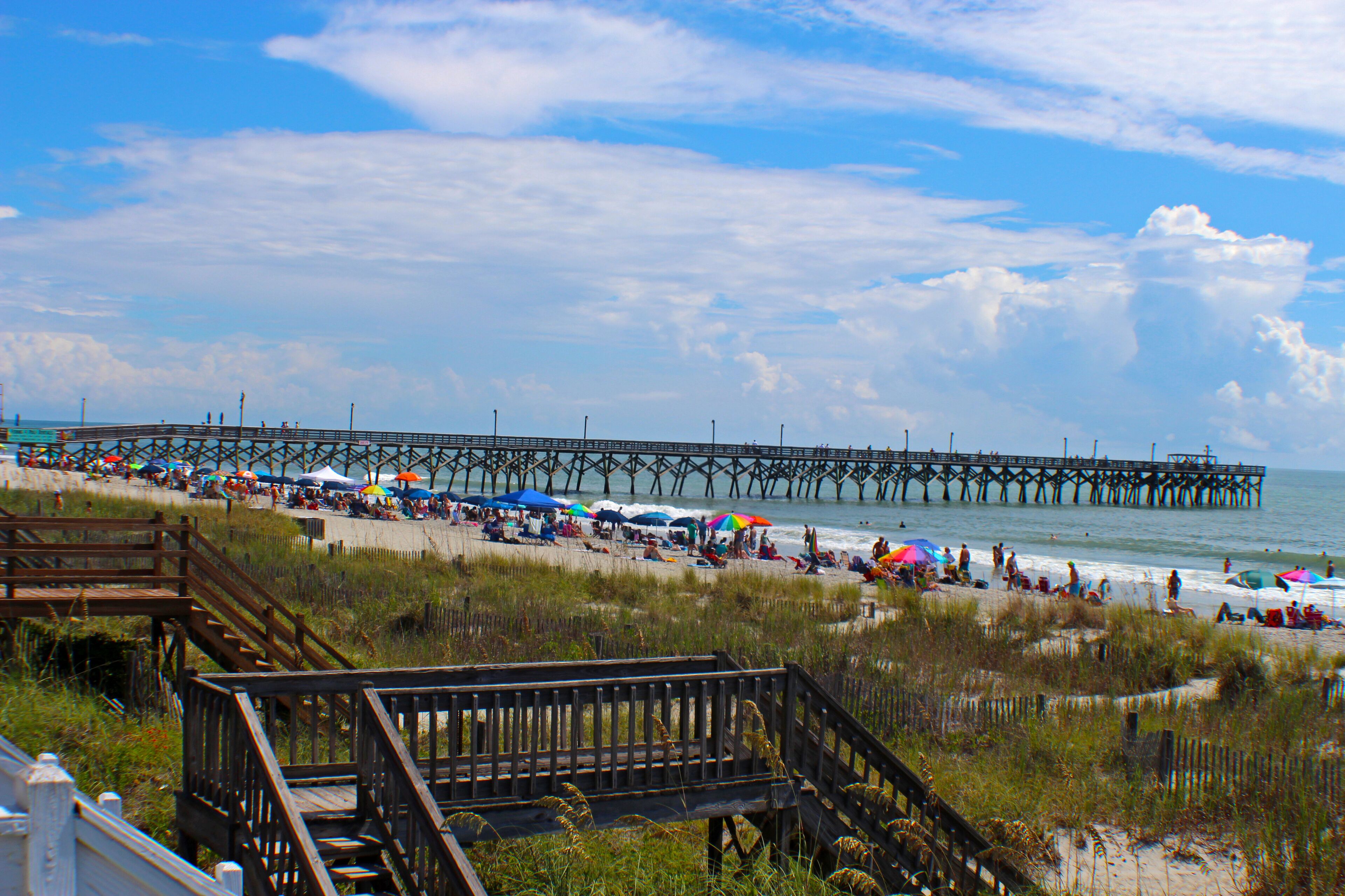 A pier extending into the water with a beach area in the foreground.