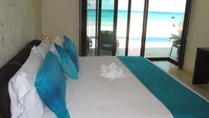 A hotel room with a bed, a view of the beach, and a balcony with chairs. - Casa Moskito, Oceanfront beautiful Villa, 150 Mbps (Playa del Carmen)