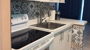 Une cuisine moderne équipée d’un four à micro-ondes, d’une cuisinière, d’un évier et d’un crédence décorée.