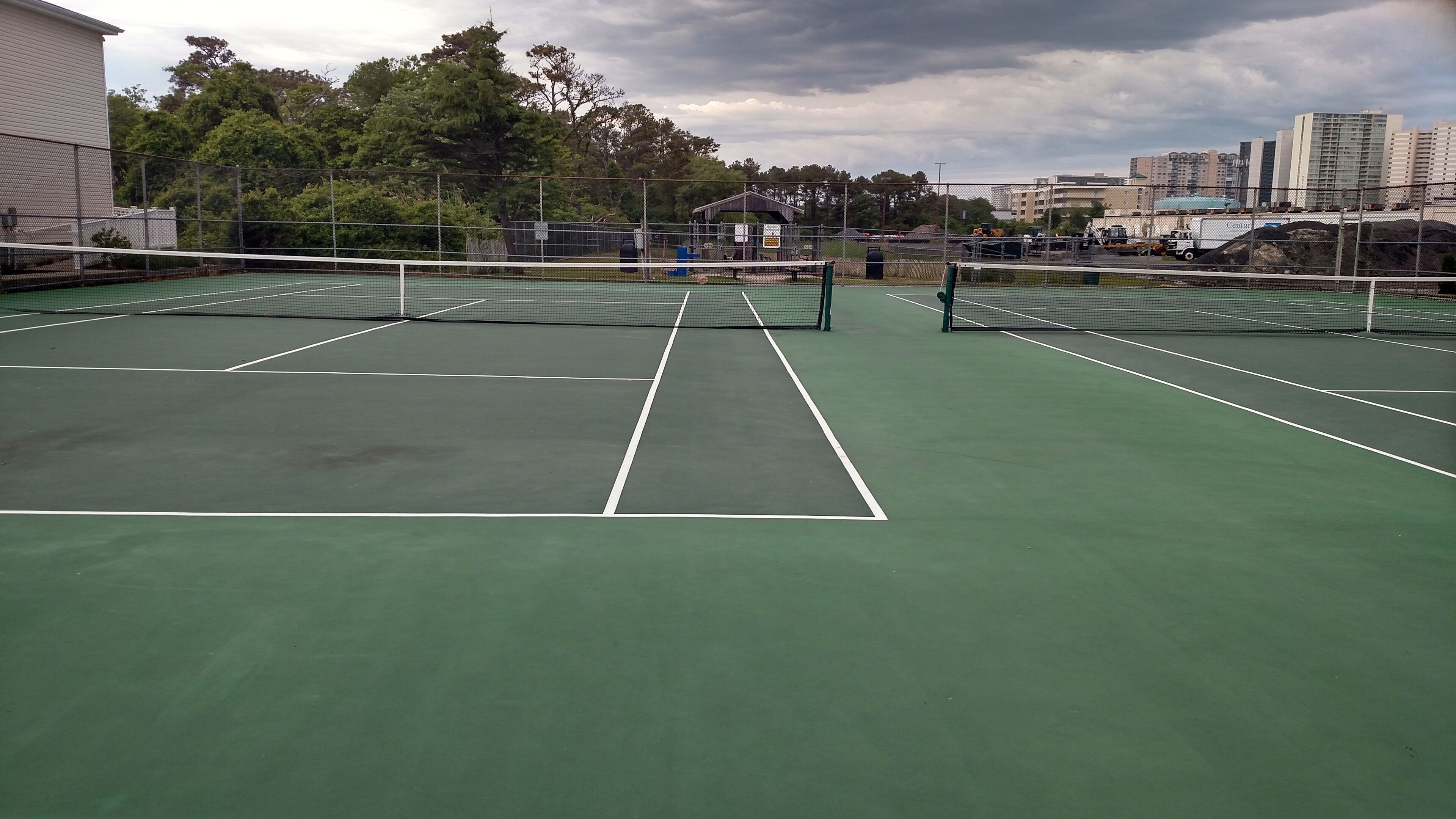 A tennis court with a net in the center, surrounded by a fence.