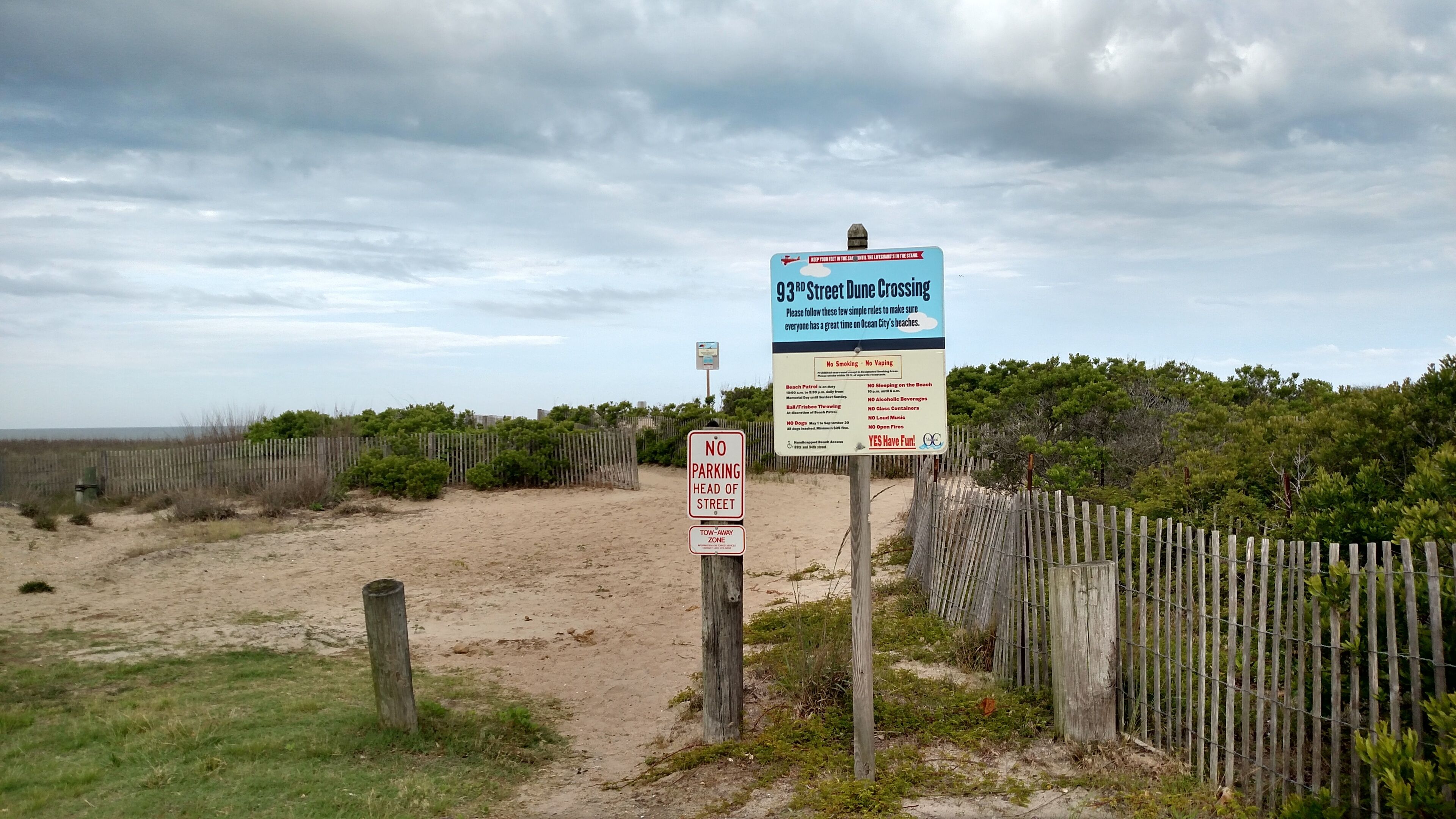 Una zona sulla spiaggia con un cartello che indica la presenza di bagnini e le regole per i frequentatori.