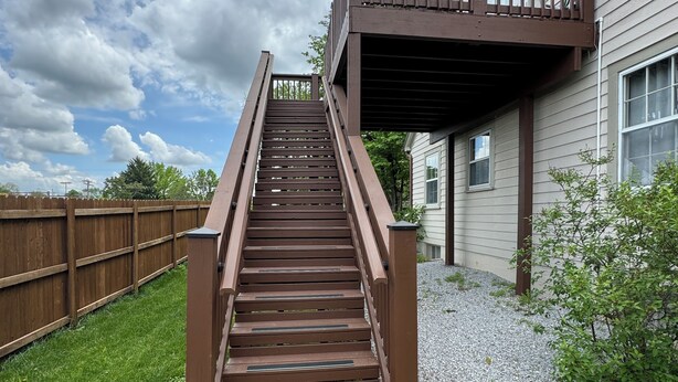 Un escalier extérieur en bois menant à une terrasse d’habitation.