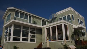 A two-story house with large windows, a covered patio, and a spiral staircase.