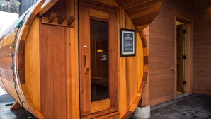 Un sauna en bois doté d’une porte en verre, d’une enseigne indiquant « BIG BEAR », et d’un mur extérieur en bois.