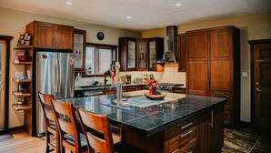 Une cuisine moderne avec des meubles en bois, un grand îlot central, des appareils en acier inoxydable et un dosseret carrelé.
