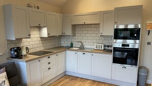 Una cocina compacta con armarios blancos, horno empotrado, tostadora y cafetera.