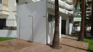A modern building with a white facade, a gated entrance, and a paved walkway.