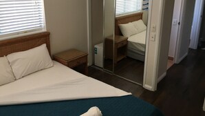 A bedroom with a bed, a wardrobe, and a mirror.