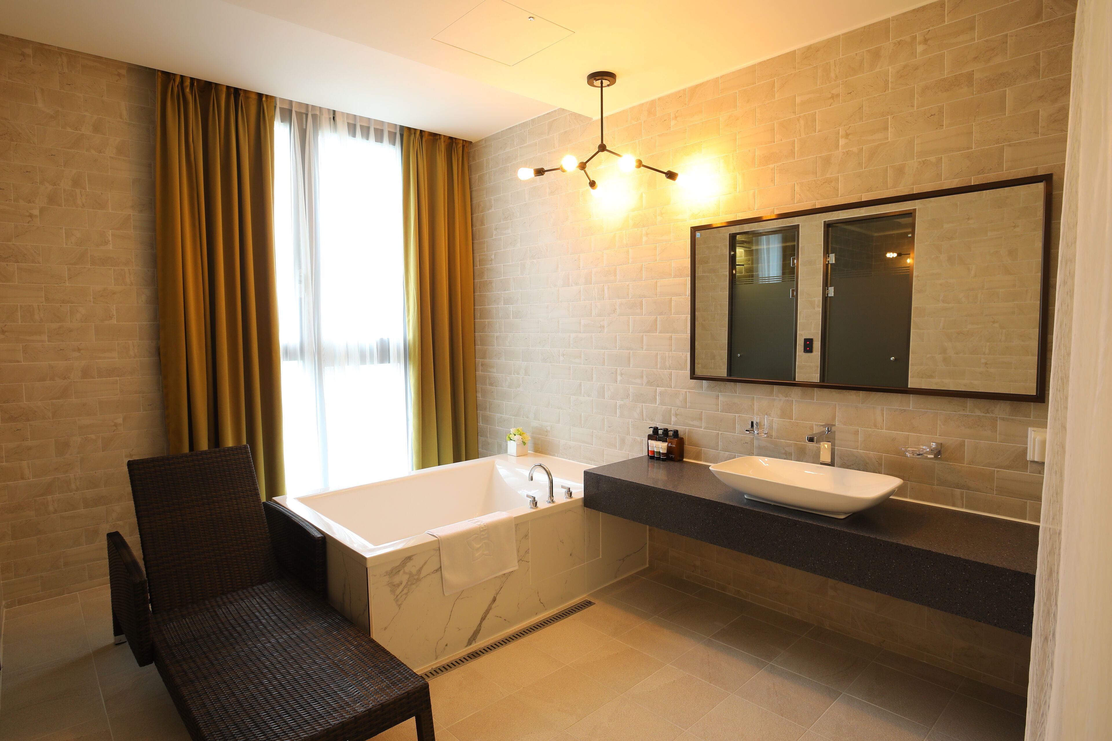 A modern bathroom with a bathtub, a sink, and a chair.