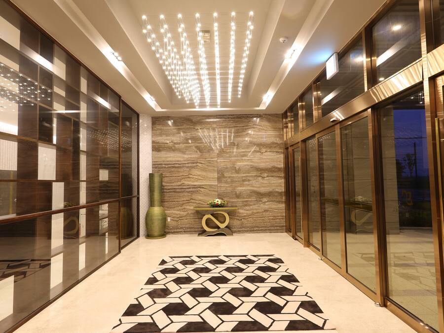 Um corredor moderno com piso estampado, portas de vidro e um lustre decorativo.
