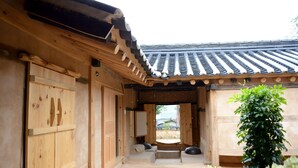 A traditional wooden building with a tiled roof, stone pathway, and a small garden area with plants. - Jukheon Traditional House (Andong)