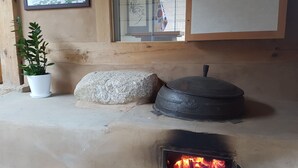 A fireplace with a stone hearth, a potted plant, and a framed picture on the wall. - Jukheon Traditional House (Andong)