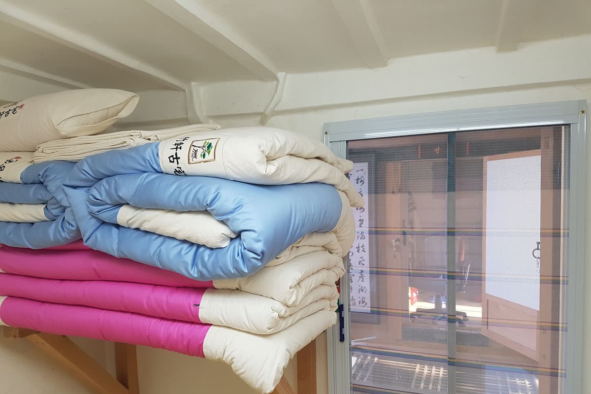 A stack of pillows in various colors on a shelf.