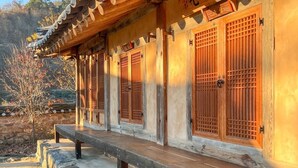 A traditional wooden building with a covered walkway and stone steps. - Jukheon Traditional House (Andong)
