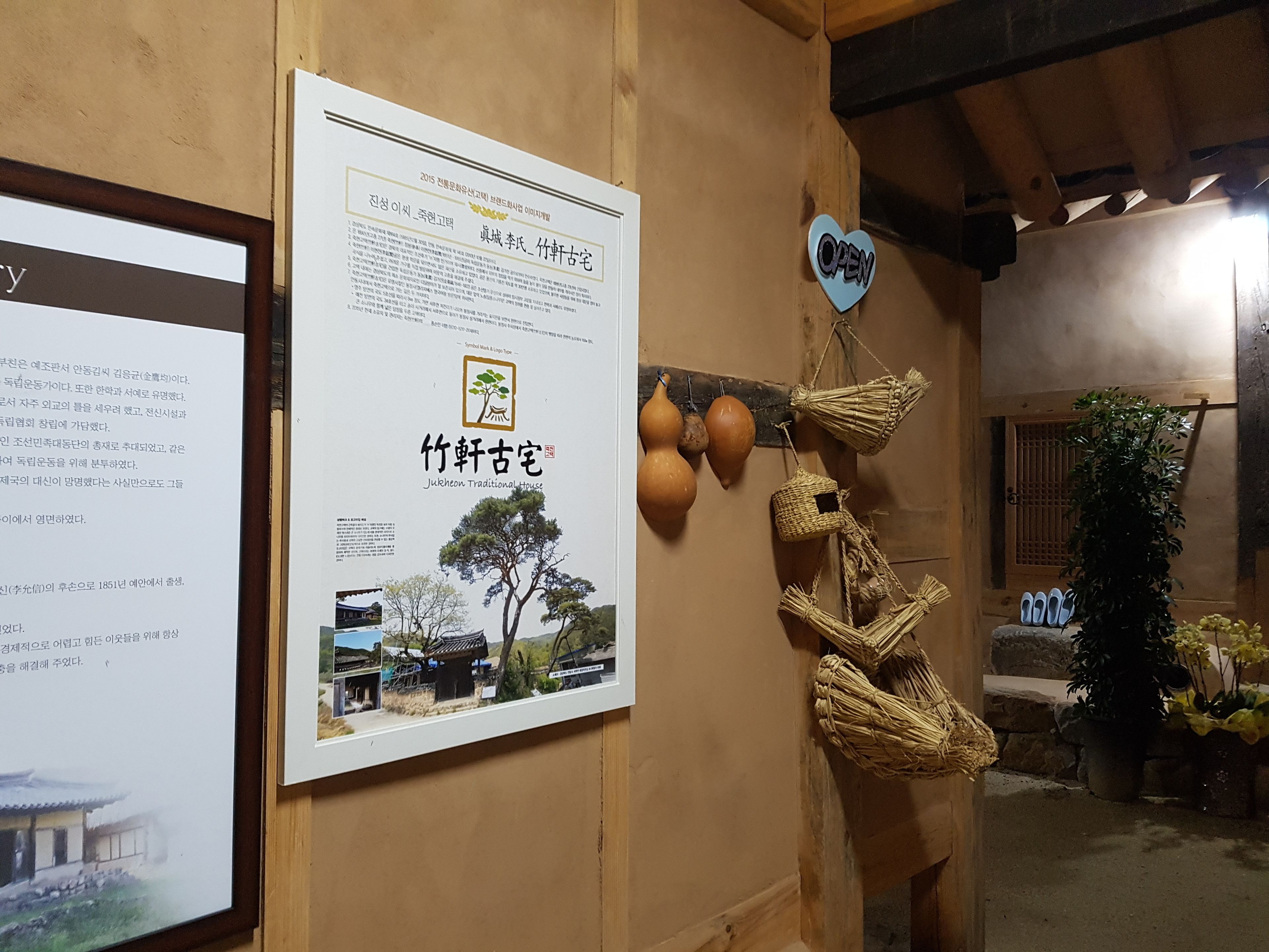 Ein traditionelles koreanisches Haus mit Holzvertäfelungen, einem Poster mit koreanischen Schriftzeichen und einem herzförmigen Schild, das auf Betrieb hinweist.