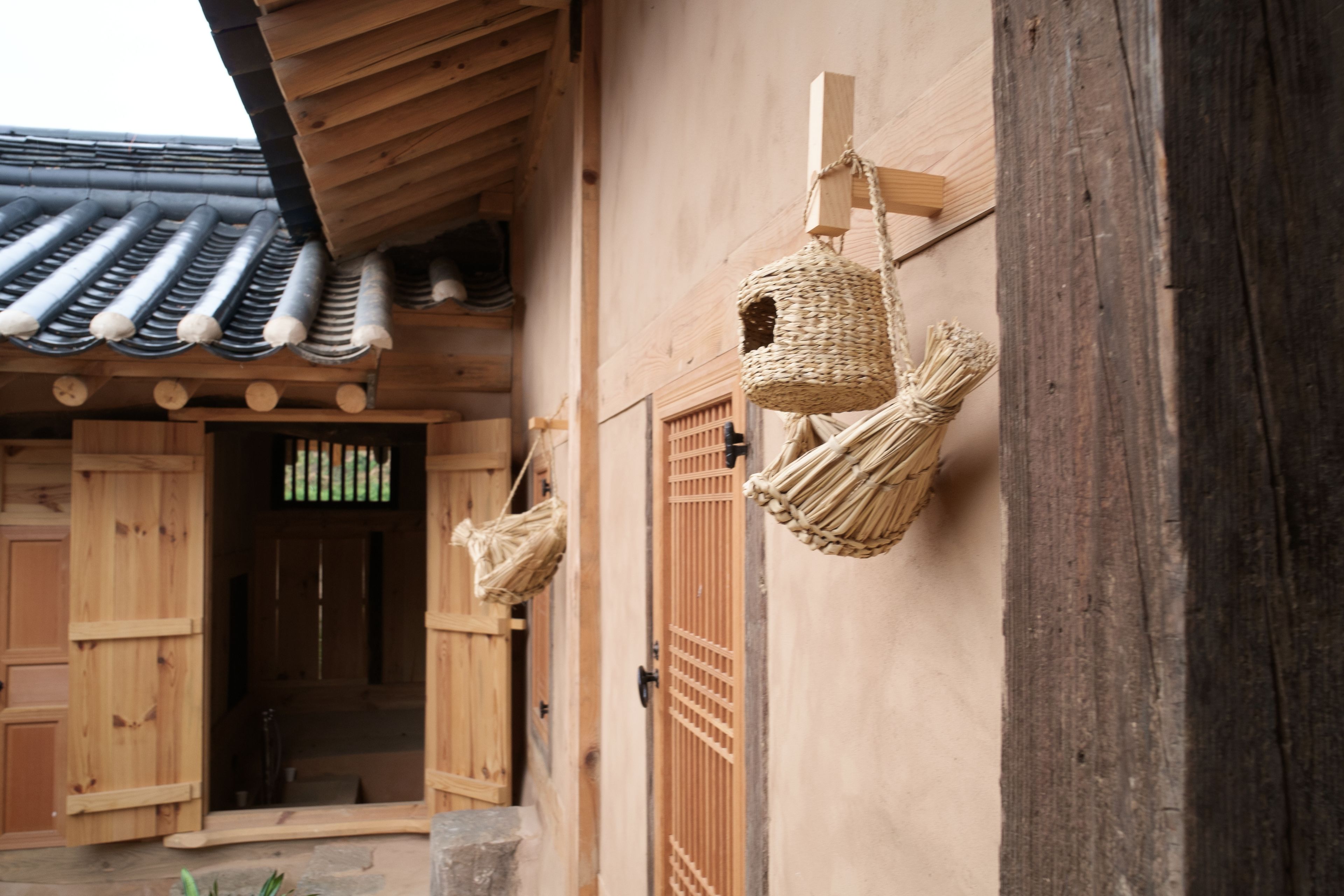 Un edificio tradicional de madera con techo de tejas, puertas de madera y cestas tejidas colgadas en la pared.