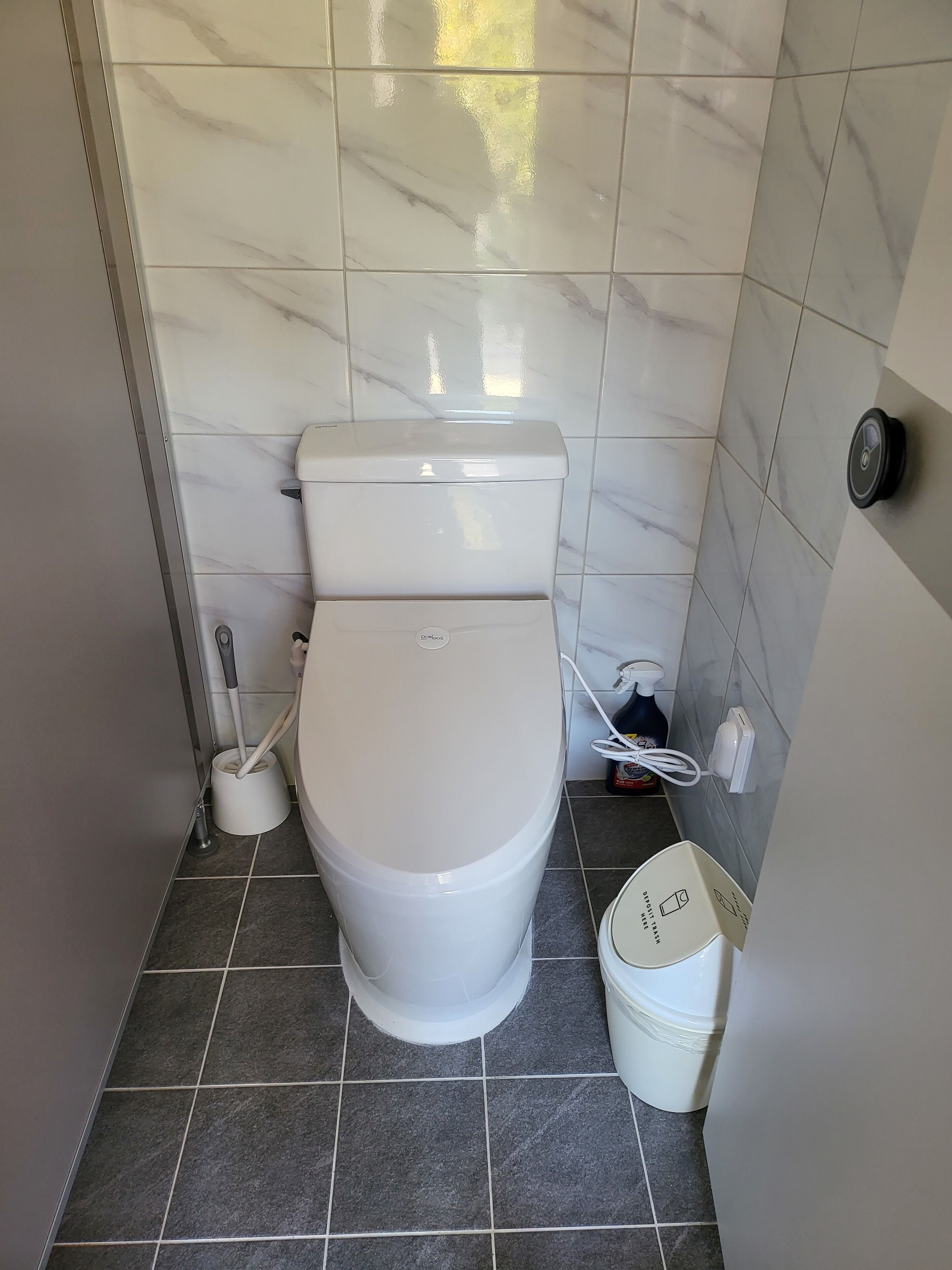 Un baño moderno con inodoro, bidé, secador de manos y cubo de basura.