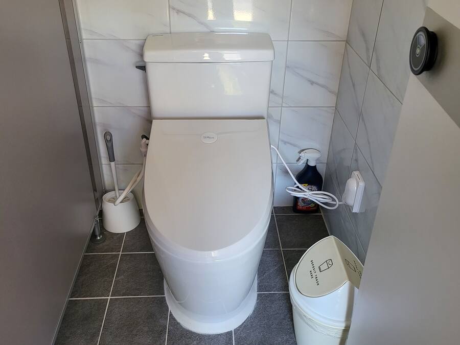 Un baño moderno con inodoro, bidé, secador de manos y cubo de basura.