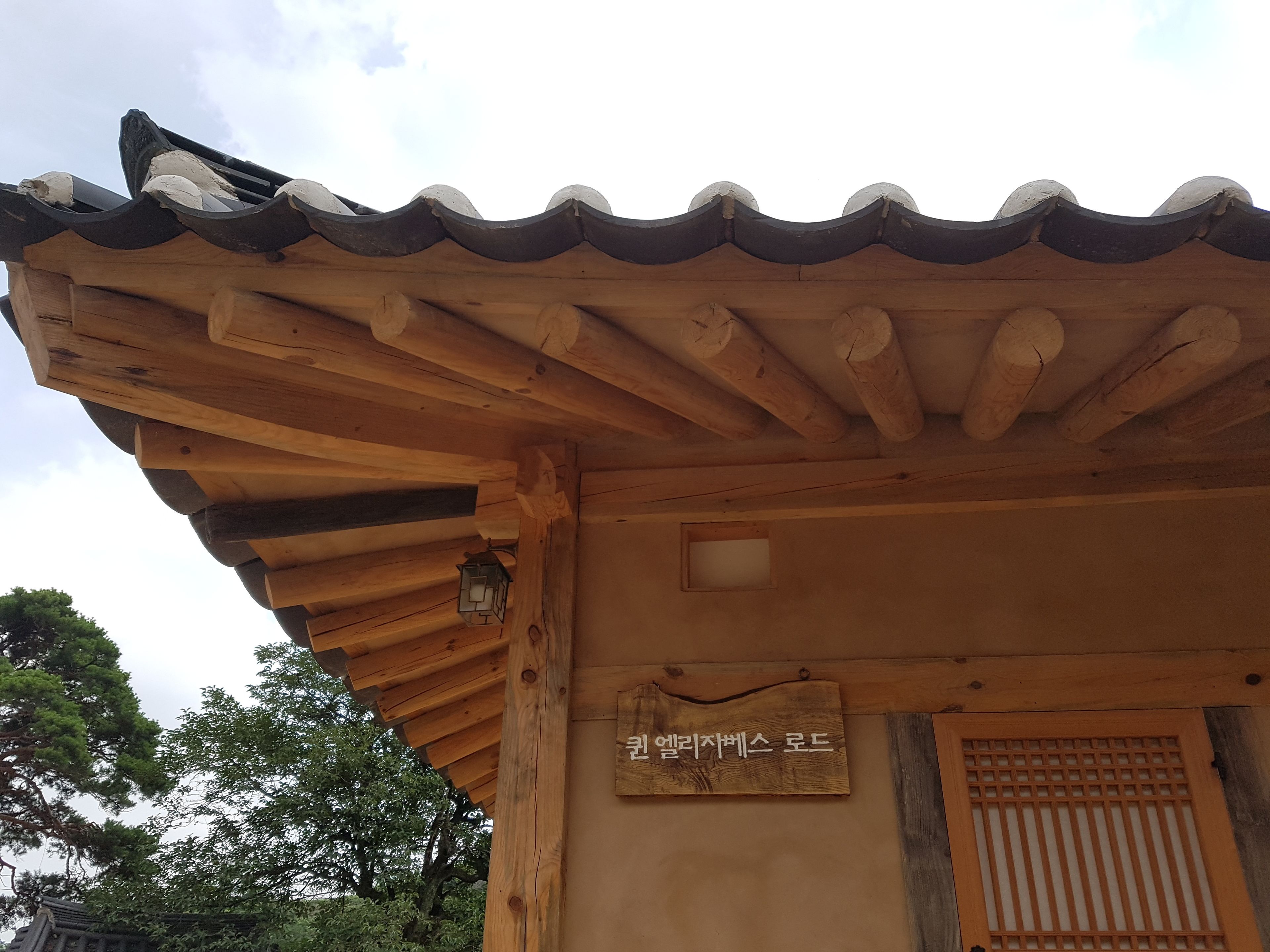 A traditional wooden structure with a tiled roof and a wooden signboard.