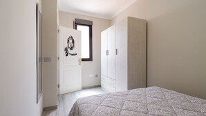 Et soveværelse med seng, garderobe og en dør med et Buddha-billede.