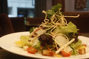 A plate of salad with various ingredients including lettuce, tomatoes, and croutons. - Herald Suites Polaris (Makati)
