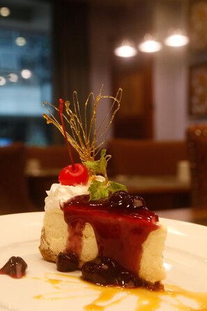 A dessert with whipped cream, cherries, and a berry sauce on a plate. - Herald Suites Polaris (Makati)